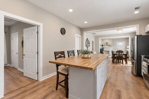 A kitchen with a wooden island, white cabinetry, and a stainless steel refrigerator. - The Runway Retreat - 8 minutes to ATL Airport! (Atlanta)