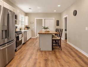 A modern kitchen with stainless steel appliances, a wooden dining table, and a central island. - The Runway Retreat - 8 minutes to ATL Airport! (Atlanta)