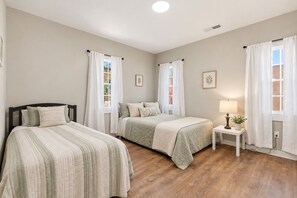 A bedroom with two beds, a bedside table with a lamp, and a window with curtains. - The Runway Retreat - 8 minutes to ATL Airport! (Atlanta)