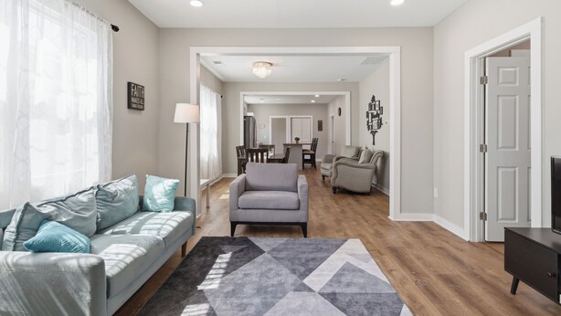 A modern living room with a sofa, a coffee table, and a TV stand. There is a dining area with a table and chairs, and a hallway leading to other rooms. - New Listing! The Landing Pad - 8 minutes to ATL Airport! (Atlanta)