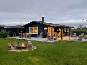 Une maison dotée d’un patio, d’un espace salon extérieur, d’un foyer et d’un jardin.