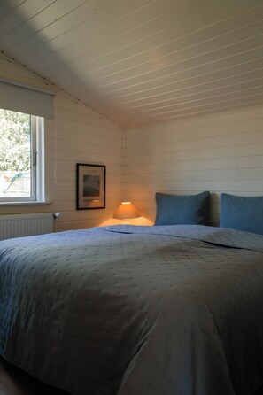 A bedroom with a bed, a window, a wall-mounted picture, and a bedside lamp. - Lovely holiday home for the whole family (Vig)