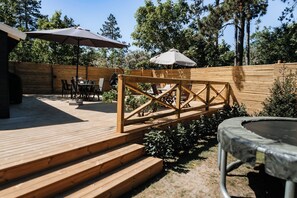 A wooden deck with outdoor furniture, a trampoline, and a wooden fence. - Lovely holiday home for the whole family (Vig)