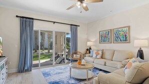 A living room with a sofa, coffee table, and artwork on the wall. - Bright Beach Condo, Pool, Spa, Comfy Beds, Patio (St. Augustine)