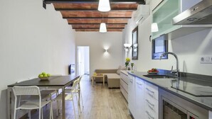 Een moderne keuken met een houten plafond, witte kasten, een inbouwoven en hanglampen.