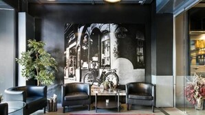 Een modern interieur met een groot raam, een rood geweven vloerkleed en twee zwarte leren fauteuils.
