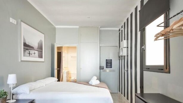 Een moderne hotelkamer met een groot bed, een nachtkastje met lamp, een kledingkast en een ingelijst schilderij aan de muur.