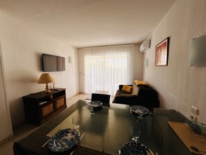 A living room with a sofa, a coffee table, and a TV mounted on the wall. - Air-conditioned apartment near the beach - 4 guests (Argelès-sur-Mer)