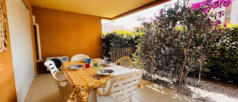 A patio with a table set for two, chairs, and a covered area.