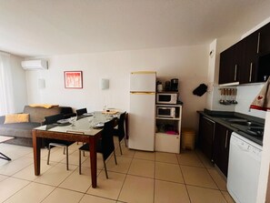 A compact living space with a dining table, chairs, a sofa, a kitchenette, and a refrigerator. - Air-conditioned apartment near the beach - 4 guests (Argelès-sur-Mer)