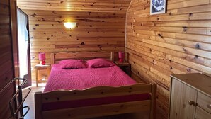 Ein Zimmer mit Holzwänden, einem Bett, Nachttischlampen und einem gerahmten Bild an der Wand.