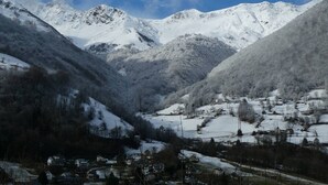 Eine gebirgige Landschaft mit schneebedeckten Gipfeln und einem Tal mit Häusern.