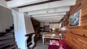 Ein gemütliches Interieur mit einer Holztreppe, einem Kamin, einem Essbereich und einer Küche.