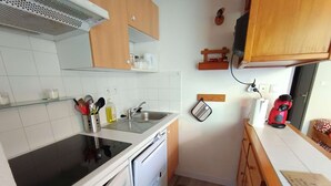 Et kompakt køkken med komfur, vask og træskabe.