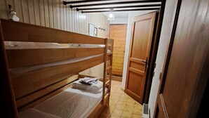 Habitación con literas, puerta de madera y suelo de baldosas.