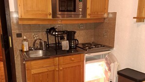 Una cocina con armarios de madera, microondas, estufa, lavaplatos y fregadero.