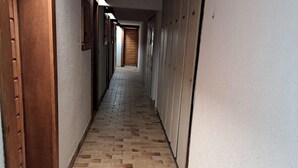 Un estrecho pasillo con suelo de ladrillo y puertas de madera a un lado.