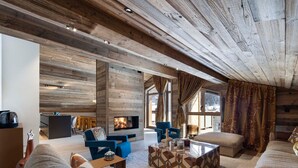 Ein geräumiger Wohnbereich mit Kamin, Holzwänden und großen Fenstern.