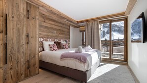 Ein Schlafzimmer mit Bett, Holzschrank und Blick auf eine verschneite Landschaft.
