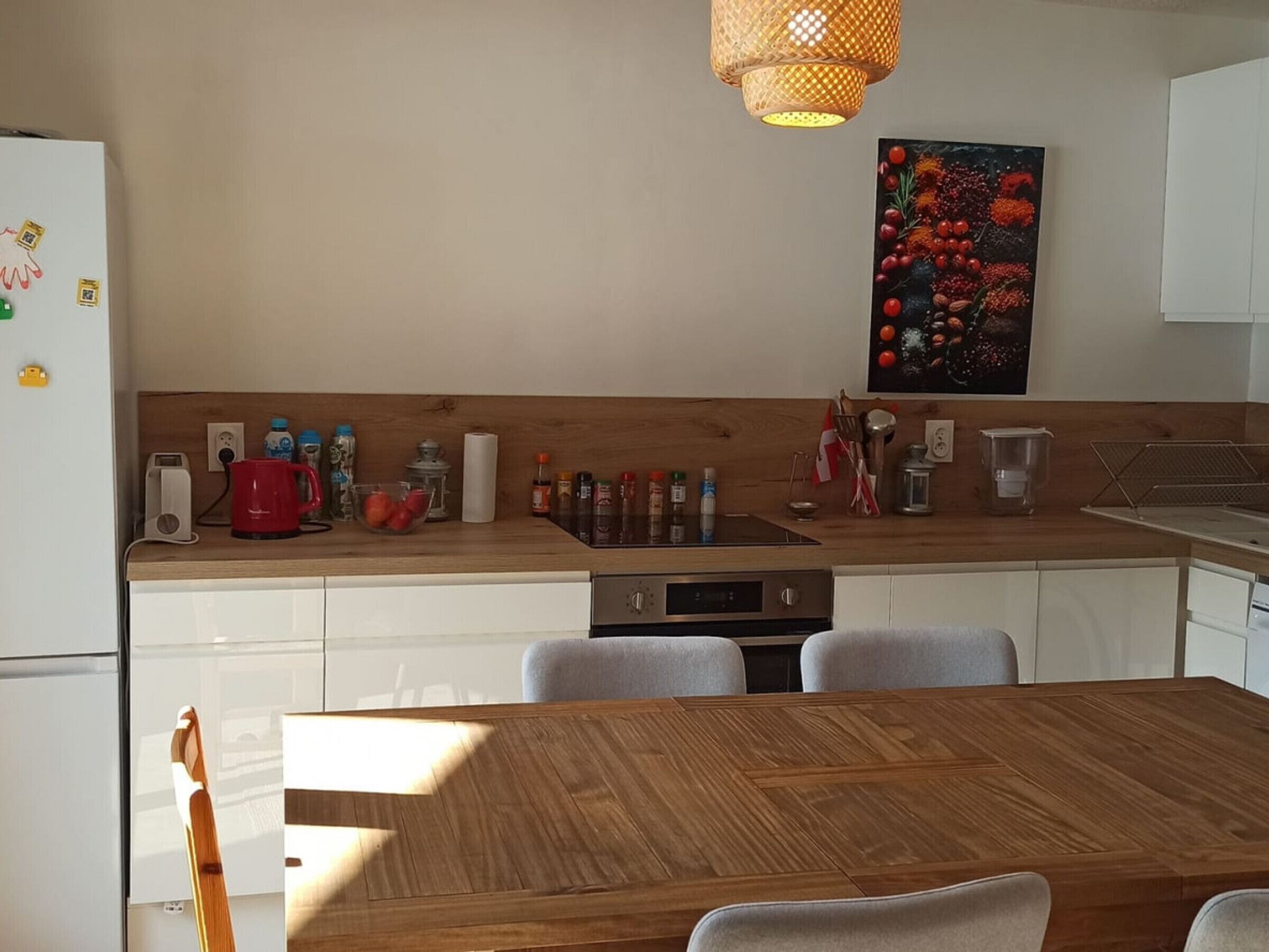 Eine moderne Küche mit weißen Schränken, einem Holztisch und einer Pendelleuchte.