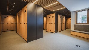 En modern hotellobby med träinredda förvaringsskåp, en sittgrupp och ett sluttande tak med inbyggd belysning.
