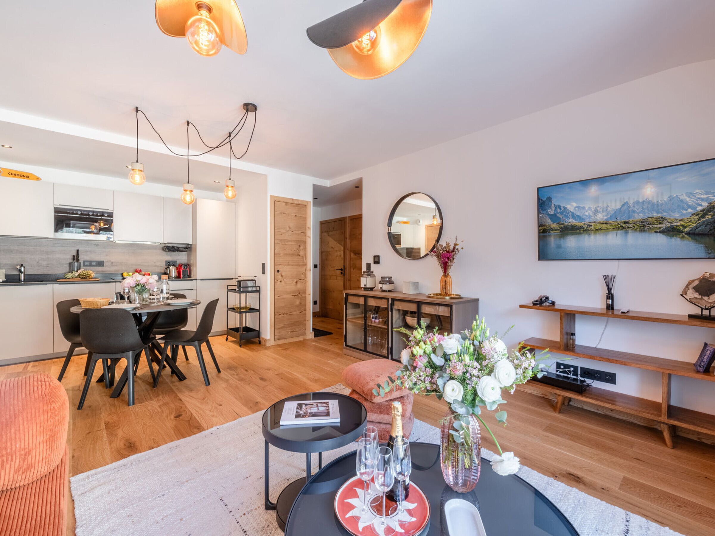 Un salon moderne comprenant un coin repas, une cuisine et une grande fenêtre donnant sur les montagnes.
