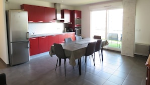 A modern kitchen with red cabinets, a dining table with chairs, and a large window. - Spacious 2BR with AC and Terrace in Sète (Sète)