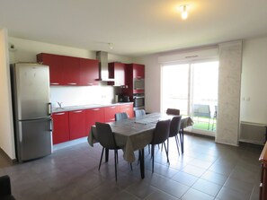 A modern kitchen with red cabinets, a dining table with chairs, and a large window. - Spacious 2BR with AC and Terrace in Sète (Sète)