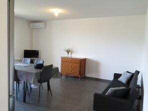 Una habitación con una mesa de comedor, sillas, un sofá, un aparador de madera y un televisor de pantalla plana.