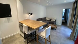 Un espacio habitable moderno con una mesa de comedor de madera, sillas blancas, un sofá gris y una lámpara de pie negra.