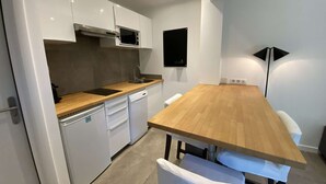 Una cocina moderna con armarios blancos, una encimera de madera y un microondas integrado.