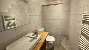 Un baño moderno con lavamanos blanco, encimera de madera y un inodoro.