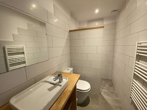 Ein modernes Badezimmer mit einem weißen Waschbecken, einer Holzausziehtheke und einer Toilette.