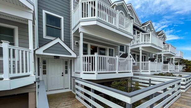 A row of coastal houses with white railings and a wooden deck. - Harbor Front Condo. Minutes to downtown. (Cape May)