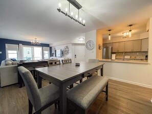 A modern kitchen with a dining area, a living room with a sofa, and a large window. - Harbor Front Condo. Minutes to downtown. (Cape May)