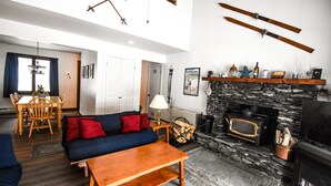 Una sala de estar con sofá, mesa, chimenea y esquíes en la pared.