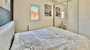 Un dormitorio con cama, radiador, ventana y espejo.