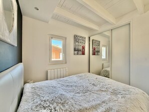 A bedroom with a bed, a radiator, a window, and a mirror. - CAP D'AGDE - Plage de la Roquille // Réf 0406 (CAP D AGDE)