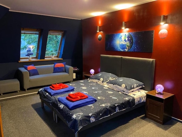 Un dormitorio con cama, sofá, mesita de noche y un globo terráqueo en la pared.