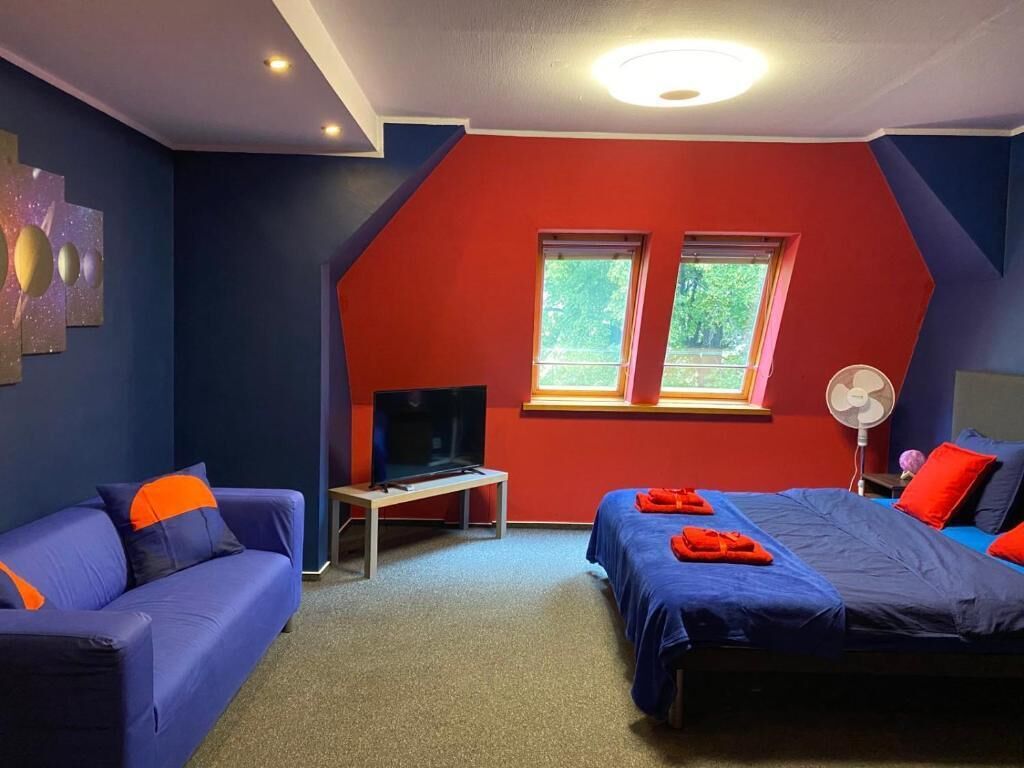 Une pièce avec un lit, un canapé, une télévision et une fenêtre.