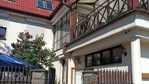 Een huis met twee verdiepingen, een balkon, stenen zuilen en een metalen hek.
