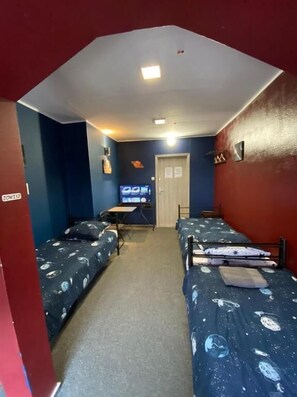 A dormitory room with two single beds, a desk, a chair, a television, and a door. - Hostel Galaxy (Gdańsk)