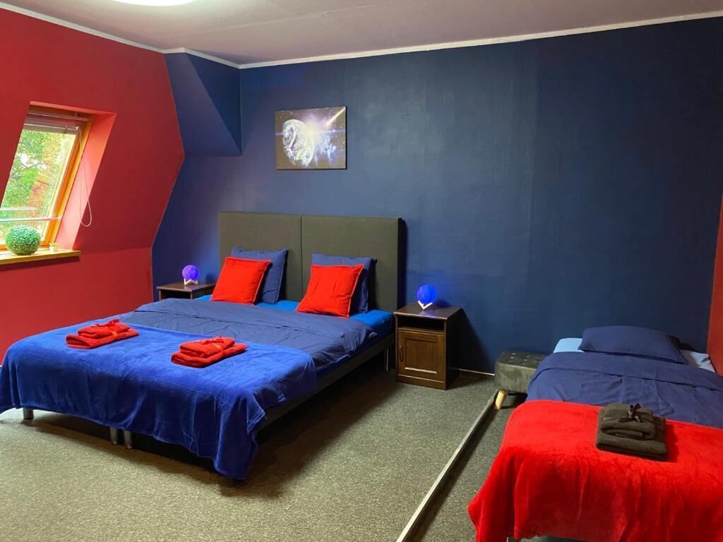 A bedroom with a bed, a nightstand, a lamp, and a window.