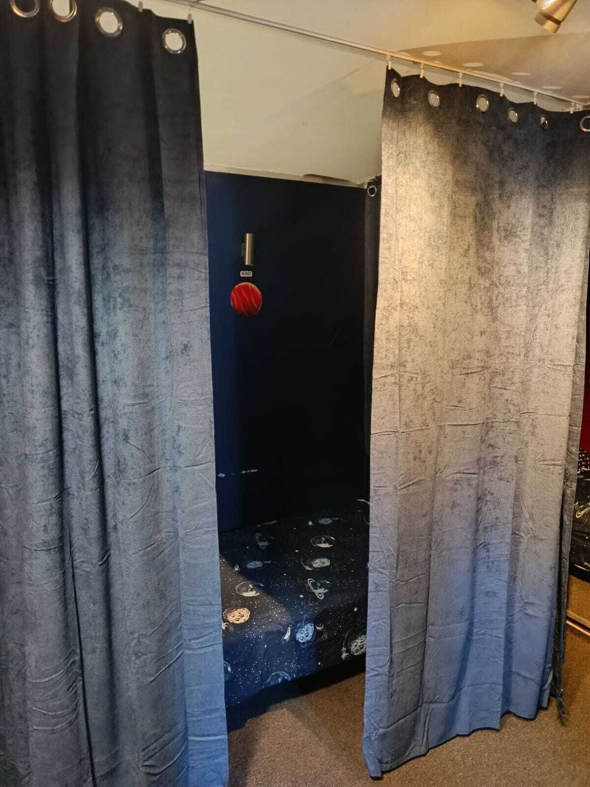 A bathroom with a shower curtain, a red circular object on the wall, and a patterned shower floor.