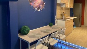 Een moderne keuken met een eethoek, inclusief unieke wanddecoratie, een houten eettafel en witte stoelen.