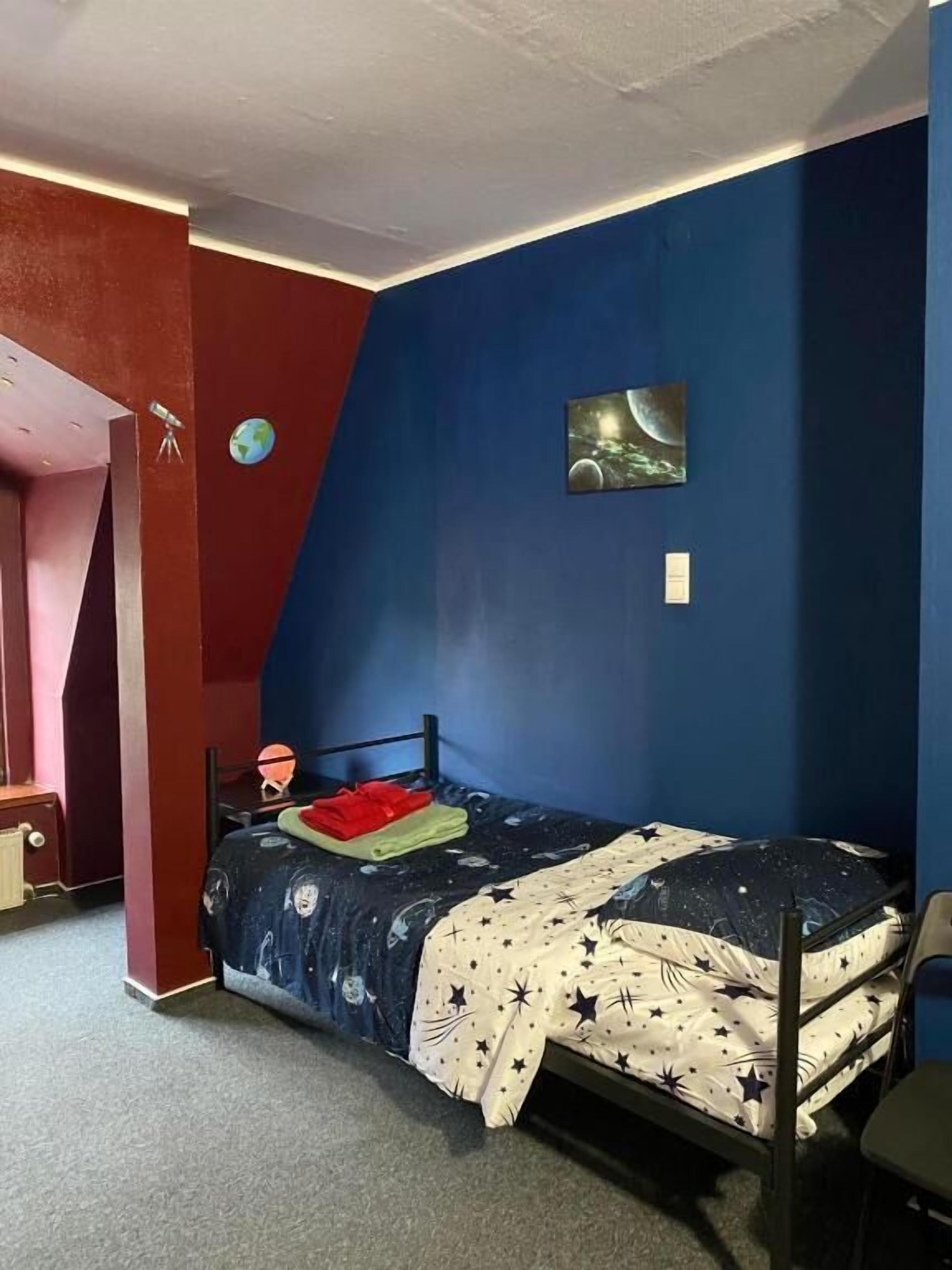 Un dormitorio con una cama litera, un escritorio, una silla, un globo terráqueo y un cuadro de un planeta.