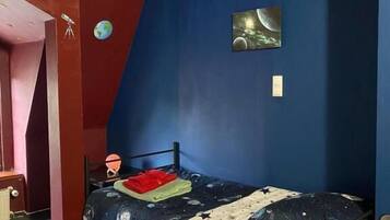 Un dormitorio con una cama litera, un escritorio, una silla, un globo terráqueo y un cuadro de un planeta.