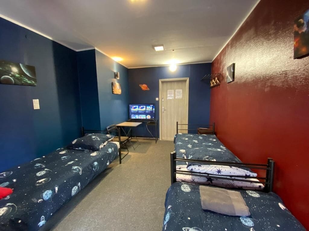 A room with two bunk beds, a desk with a computer, and a door.