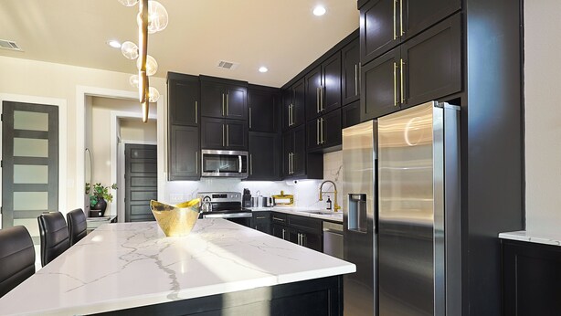 A modern kitchen with dark cabinetry, stainless steel appliances, and a marble island. - Lake on Winnetka Dream Home - Trinity Grove & Downtown Dallas (Dallas)