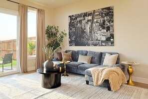 A living room with a sofa, a coffee table, a side table, a large cityscape artwork, a potted plant, and a sliding glass door. - Lake on Winnetka Dream Home - Trinity Grove & Downtown Dallas (Dallas)